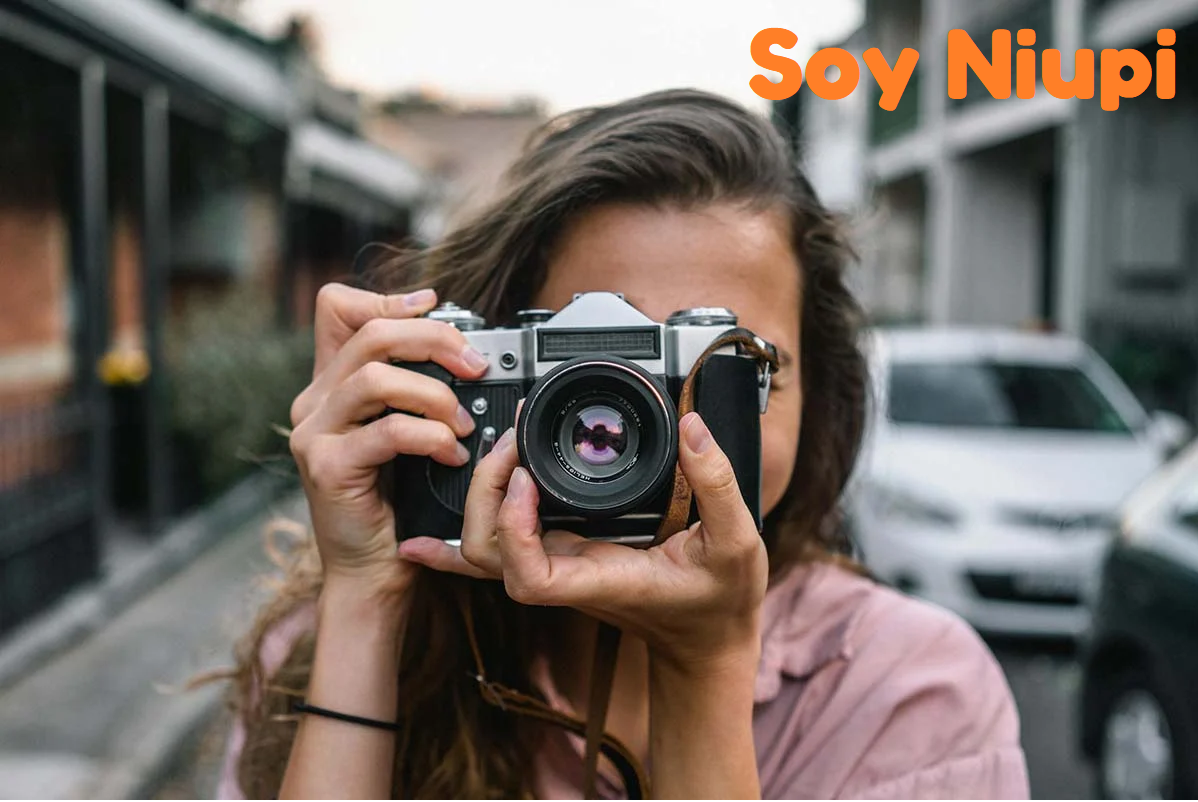 Mujer fotografiando con una cámara de película clásica en una calle urbana